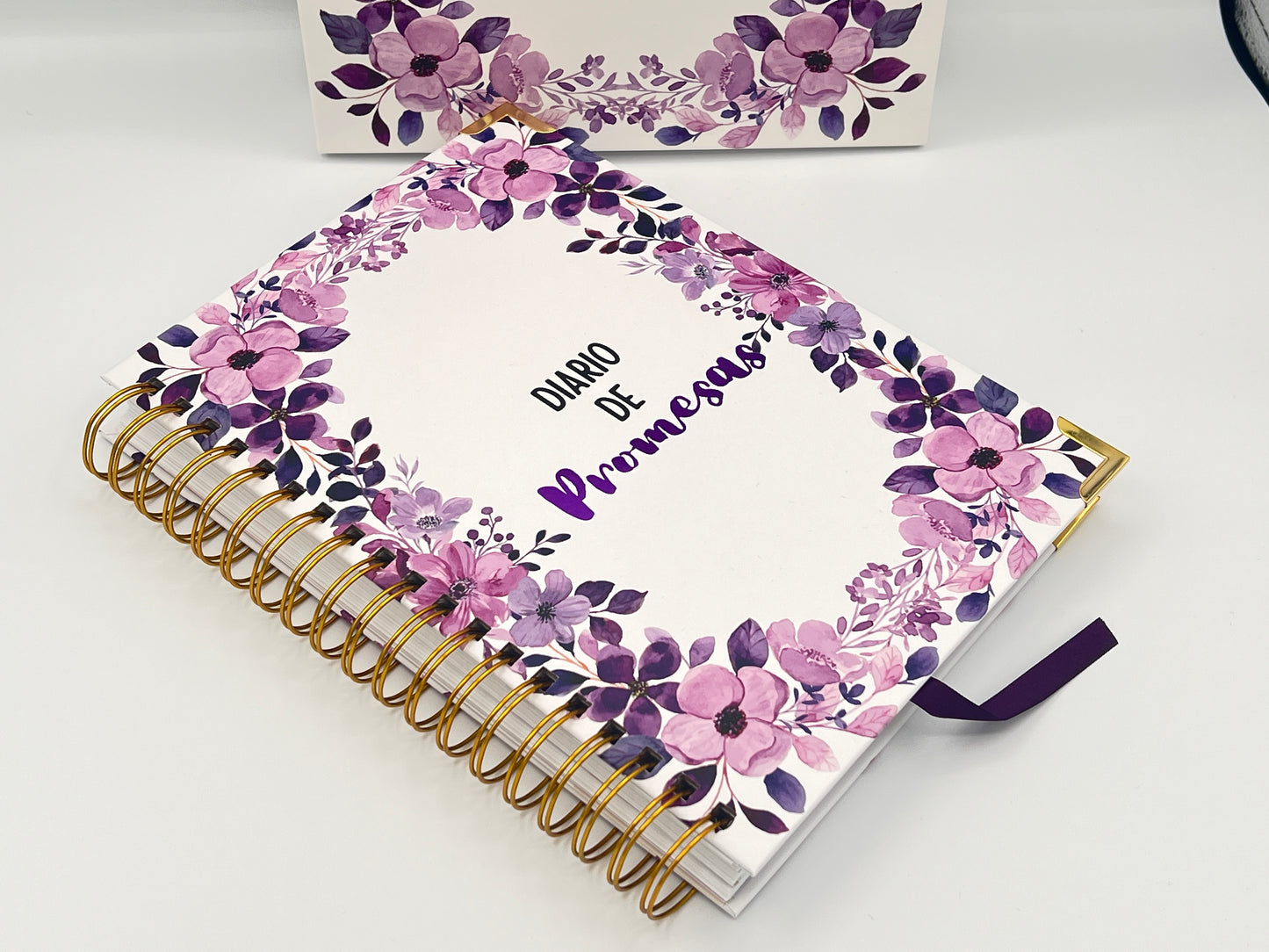 Floral notebook with gold spiral binding on a white background