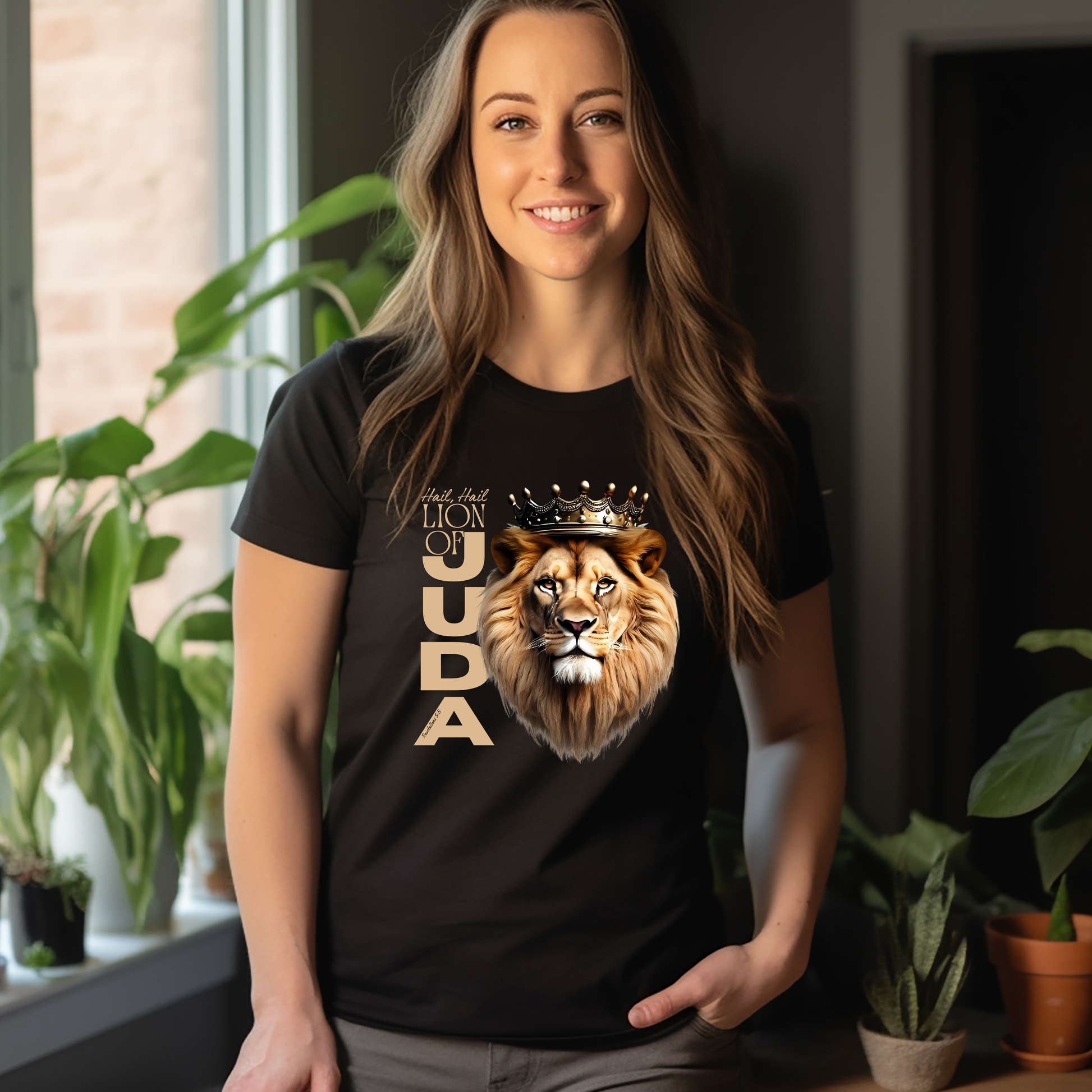 Woman wearing a black t-shirt with a lion graphic and Hail, Hail Lion of Judah, standing indoors with plants in the background.