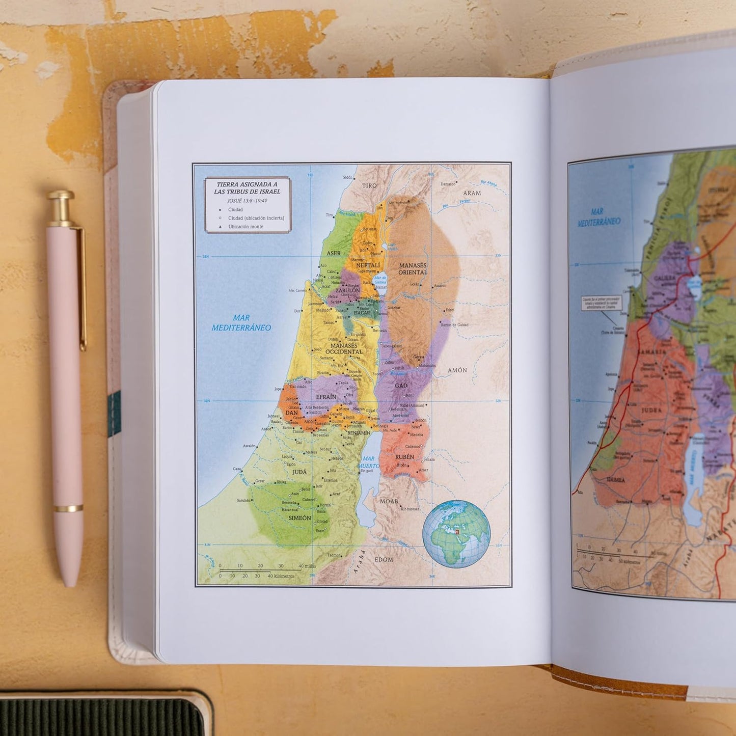 RVR 1960 Large Print Handy Size Bible – Special Watercolor Edition, Imitation Leather. Open Bible with maps of a region, pen on a wooden surface